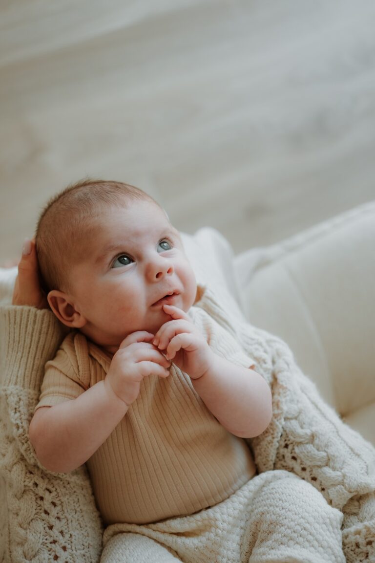 Miminko v náručí maminky si prohlíží svět na newborn focení Praha