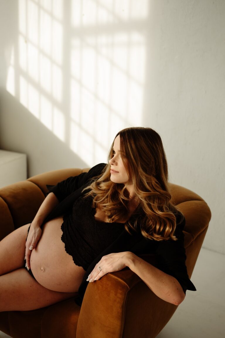 Těhotná žena si užívá čas na křesle při těhotenském focení v ateliéru Praha