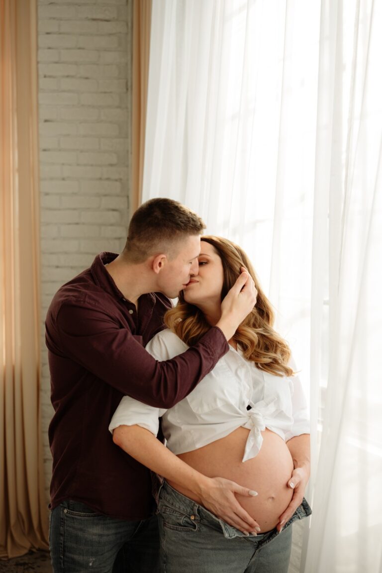 Muž líbá svou ženu při těhotenském focení v ateliéru Praha